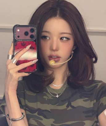 迷彩柄のトップスとマイクを身につけ、鏡越しに自撮りするウォニョン