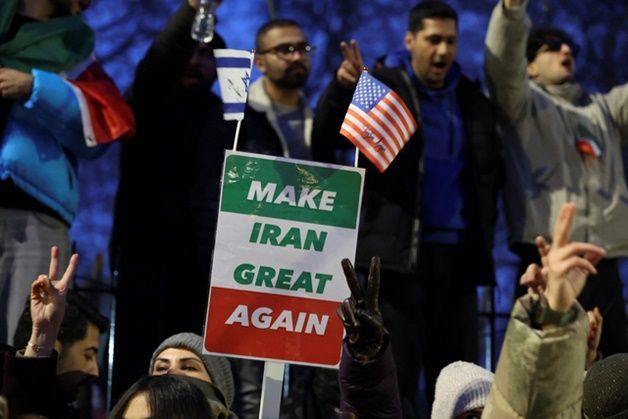 12일(현지시간) 영국 런던 주재 이란대사관 앞에서 열린 집회에 참석한 한 시민이‘이란을 다시 위대하게’라고 적힌 플래카드를 미국·이스라엘 국기와 함께 들어보이며 현재 이란 전역에서 확산하는 반정부 시위에 대한 지