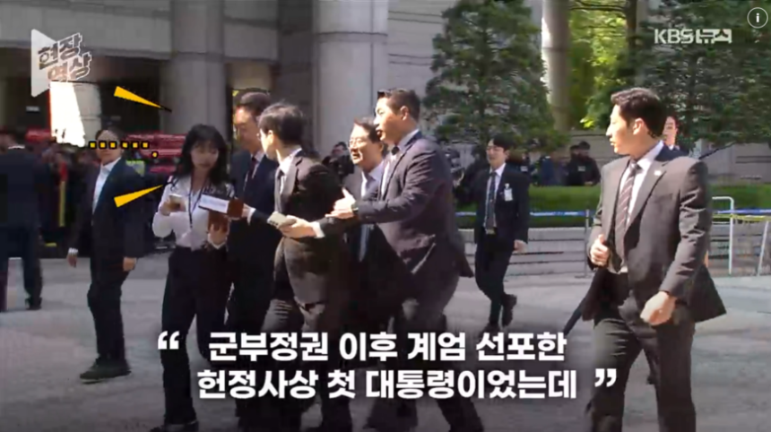 12일 오전 서울중앙지방법원에 출석한 윤석열 전 대통령에게 KBS 기자가 질문하자 경호원이 뒤에서 팔을 잡아 끌고 있다./KBS
