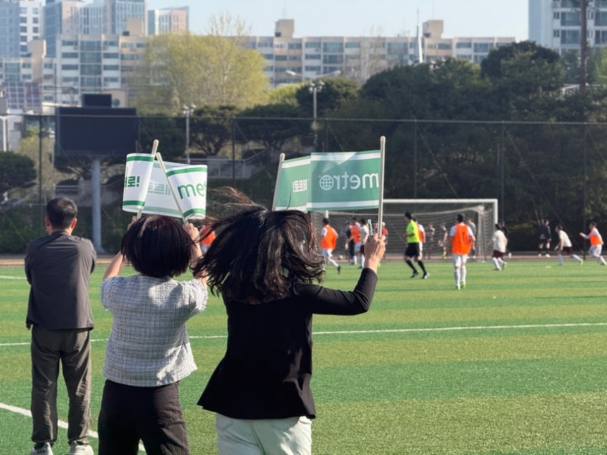 김보민 인턴 기자(왼쪽)와 이청하 기자(오른쪽)가 메트로미디어 응원 깃발을 흔들며 선수들에게 힘을 실어주고 있다. /김한내 기자