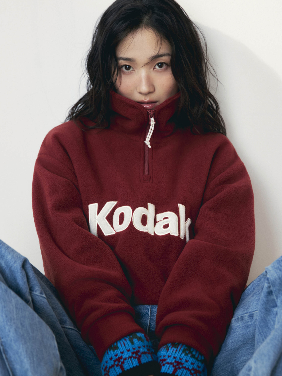 コダックのロゴが入った深紅のフリースを着て座るキム・ヘユン
