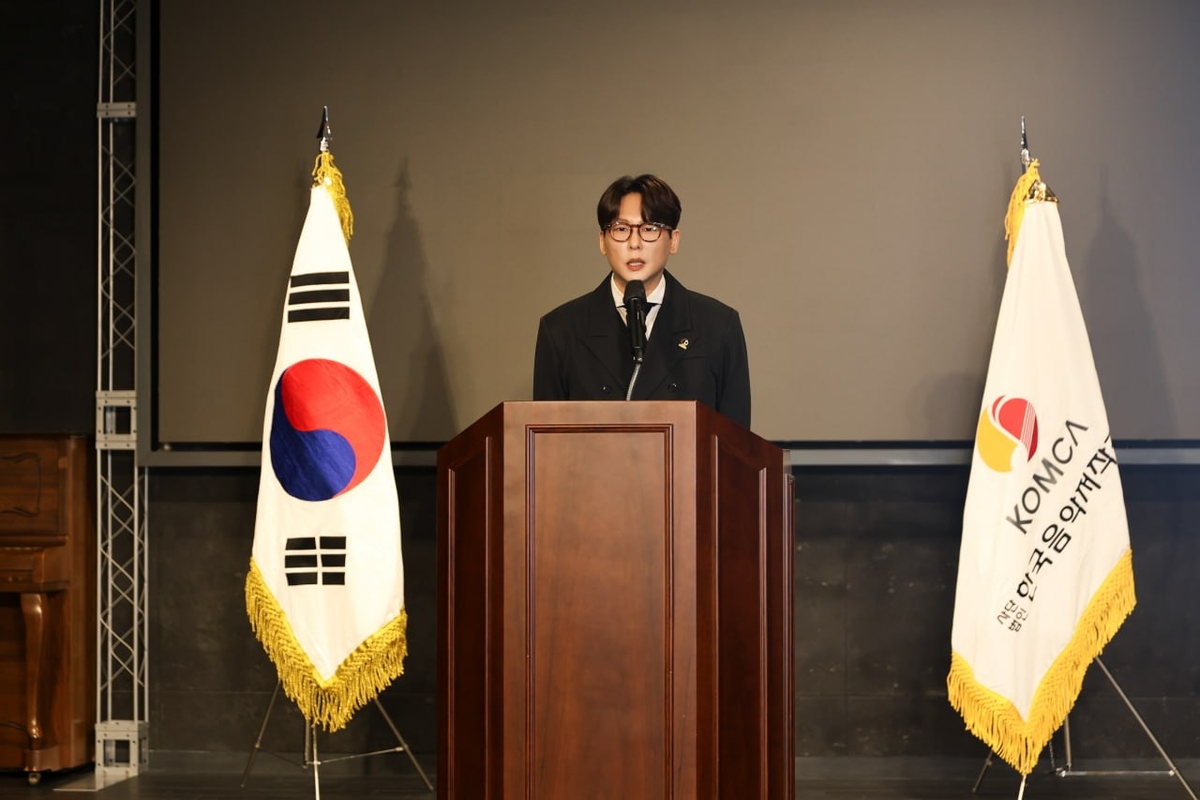 韓国音楽著作権協会の旗の間で演説するイ・シハ会長