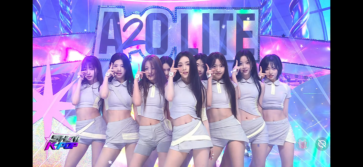 アリランTVの番組『SHOW K-POP』のステージで、グループ名のセットを背にポーズを取るA2O LITE