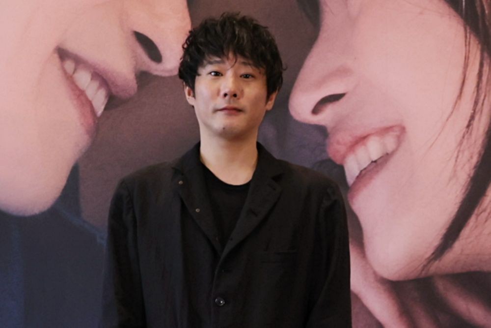 映画「그대, 별처럼」のポスターを背に立つ藤井道人監督