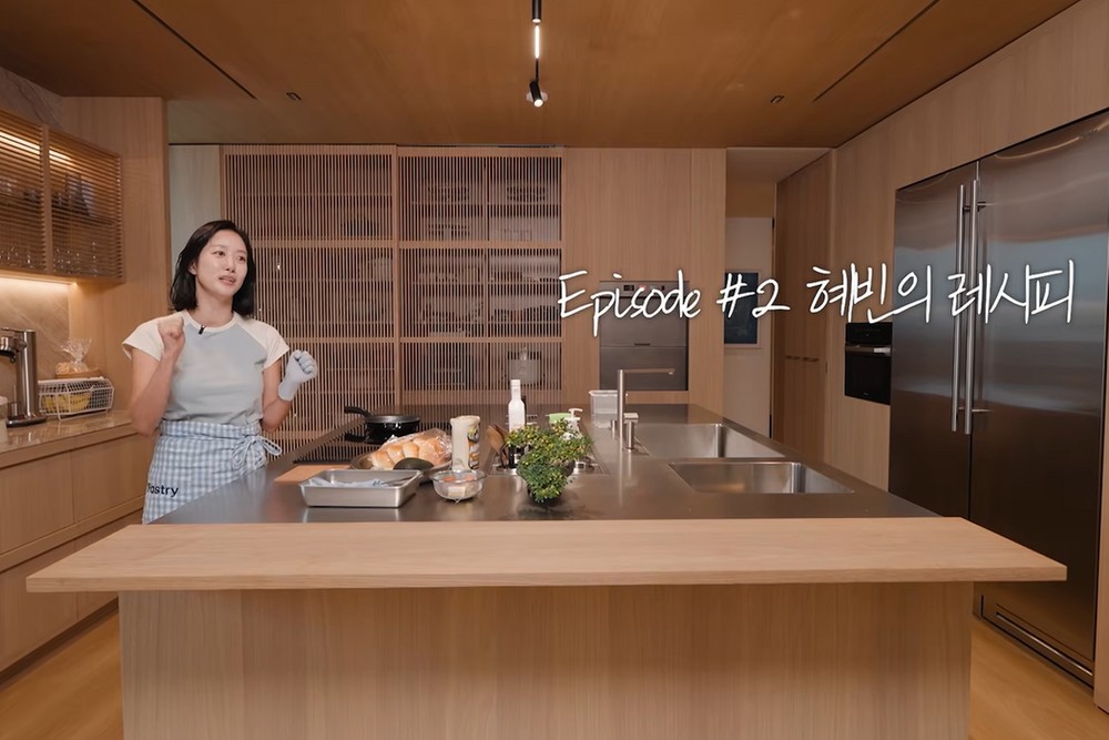 木目調の広いキッチンで料理を紹介するチョン・ヘビン。画面には「Episode #2 ヘビンのレシピ」と表示されている