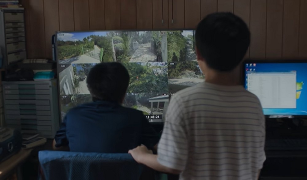 映画『可能な愛』の場面写真。監視カメラの映像を表示したモニターを見つめる二人