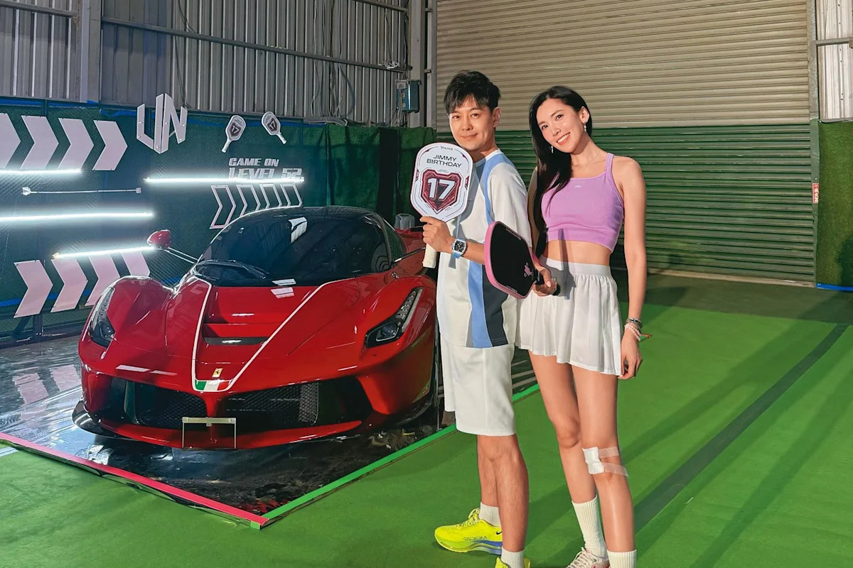 赤いフェラーリF80の横でバースデーサインを持つリン・ジーインと女性