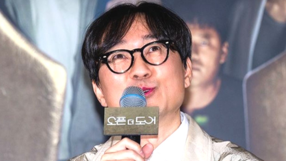 眼鏡をかけたチャン・ハンジュンがマイクを持って話す様子