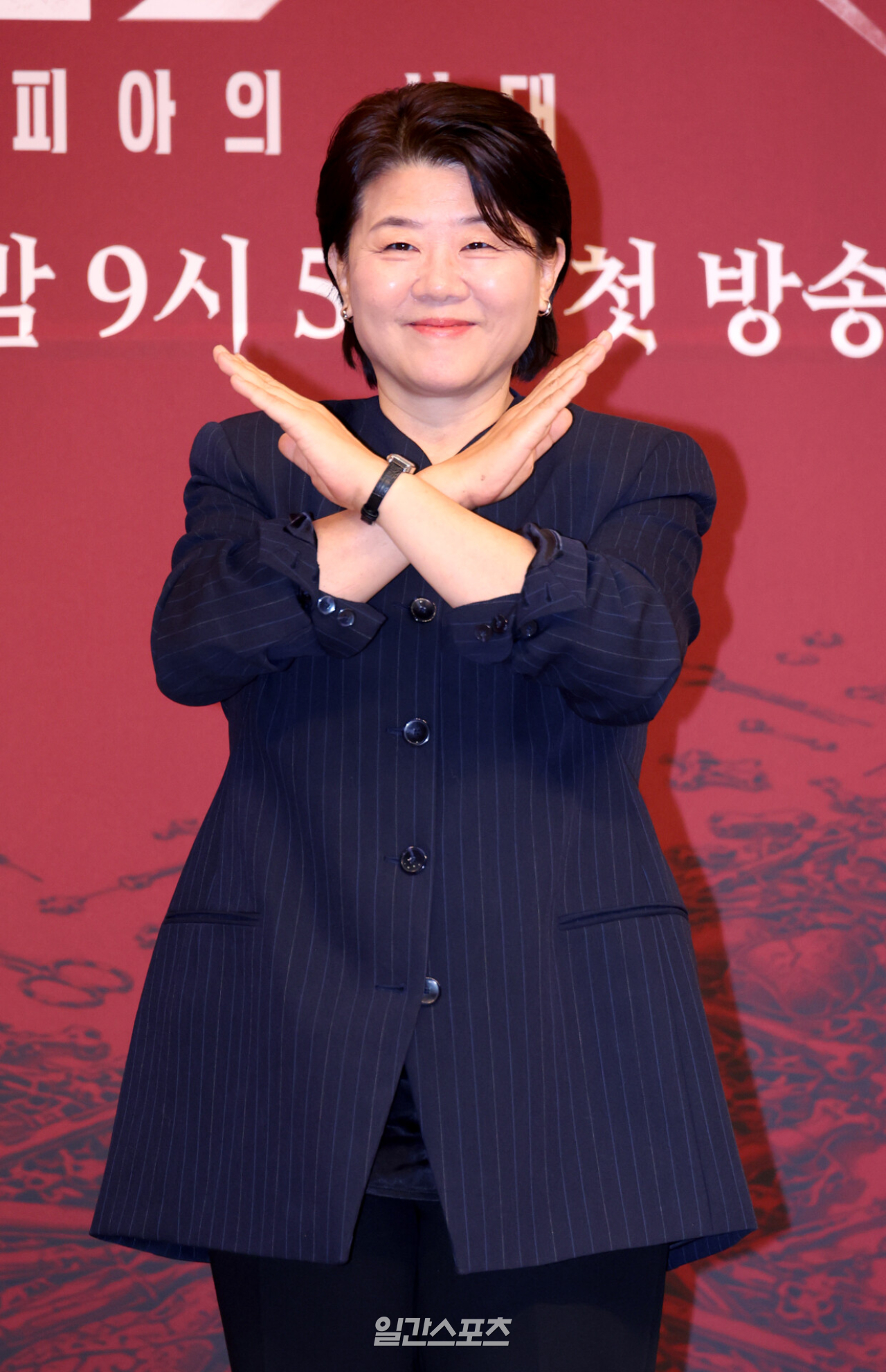 紺色のジャケット姿で腕を交差させて笑顔を見せるイ・ジョンウン