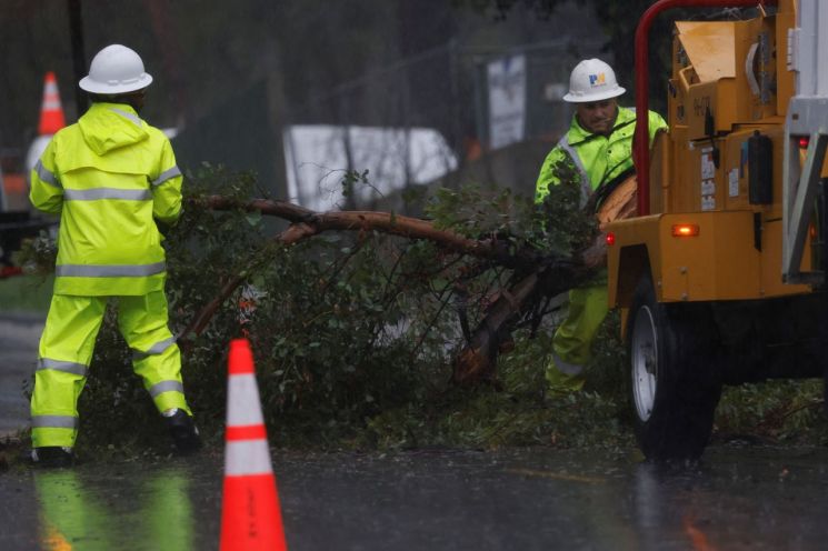 12월 24일,미국 캘리포니아 알타데나에서 폭우가 내리자 LA 카운티 공공사업국 직원이 쓰러진 나무를 제거하고 있다.로이터연합뉴스
