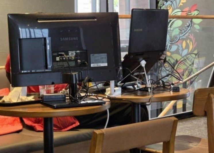 컴퓨터 모니터 등 온갖 개인 장비를 들고 테이블 두 개를 사용해 개인 업무를 하고 있는 한 고객의 모습. 엑스 캡처