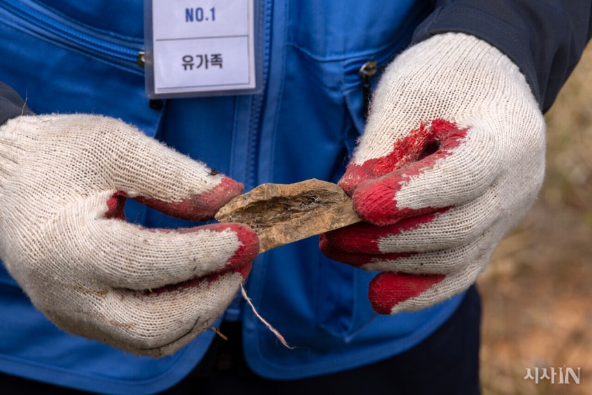 4월13일 오전 무안공항 참사 희생자 유해와 유류품을 찾기 위한 전면 재수색이 시작된 가운데 한 유가족이 희생자의 것으로 보이는 뼛조각을 들어 보이고 있다. 유가족이 콘크리트 둔덕 앞에서 직접 발견했다. ©