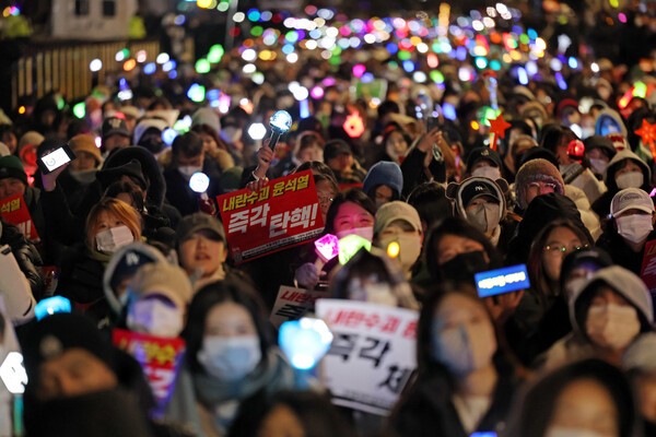 서울 여의도 국회 앞에서 열린 윤석열 탄핵 및 구속을 촉구하는 촛불문화제에서 참가자들이 관련 손팻말과 응원봉을 들고 있는 모습.ⓒ연합뉴스