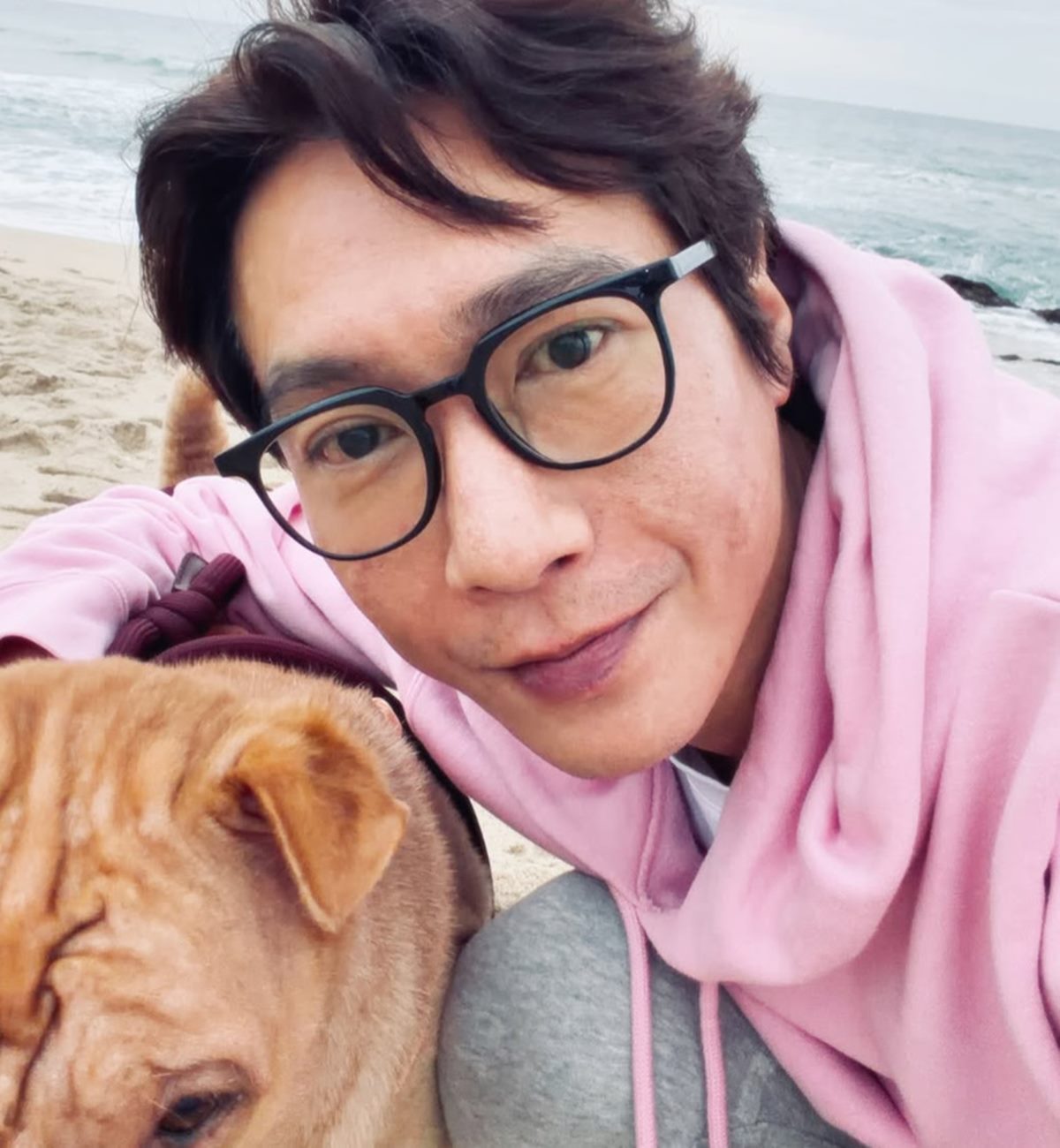 ピンクのパーカー姿で、海辺の愛犬と顔を寄せるコ・ジヨン