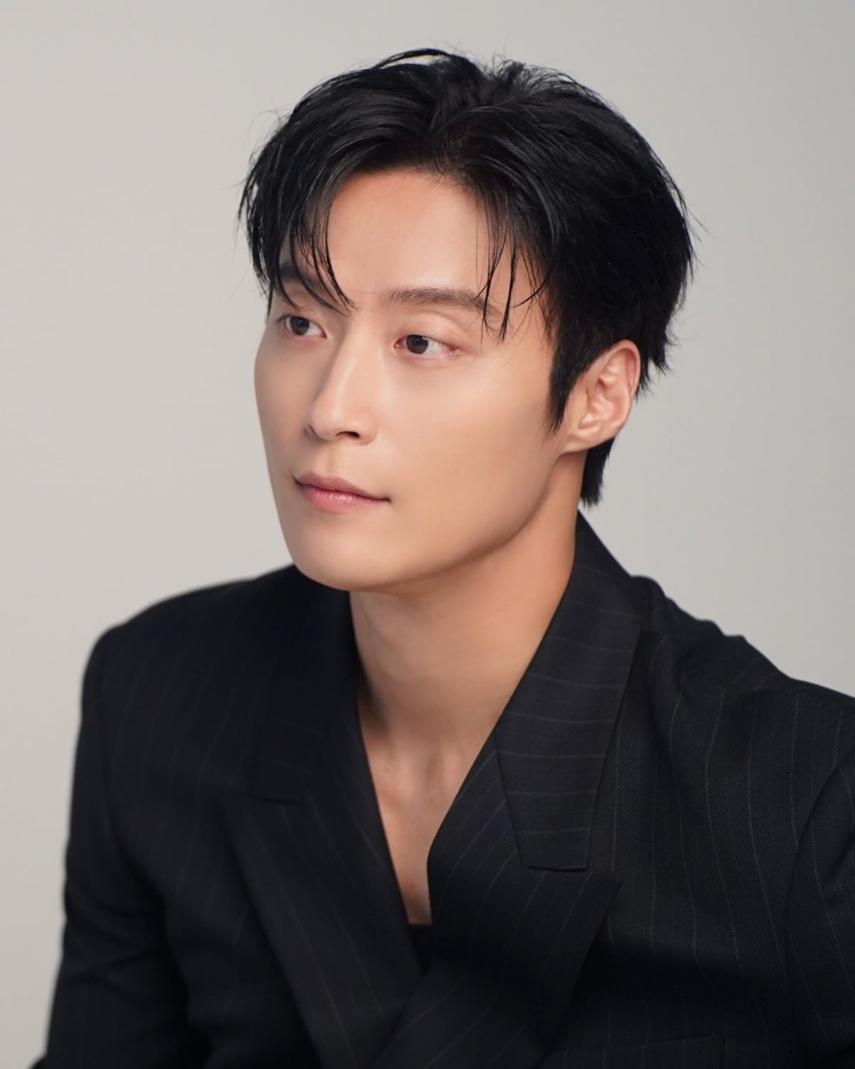 黒いストライプ柄のジャケットを着て横を見つめる俳優ホ・ナムジュン