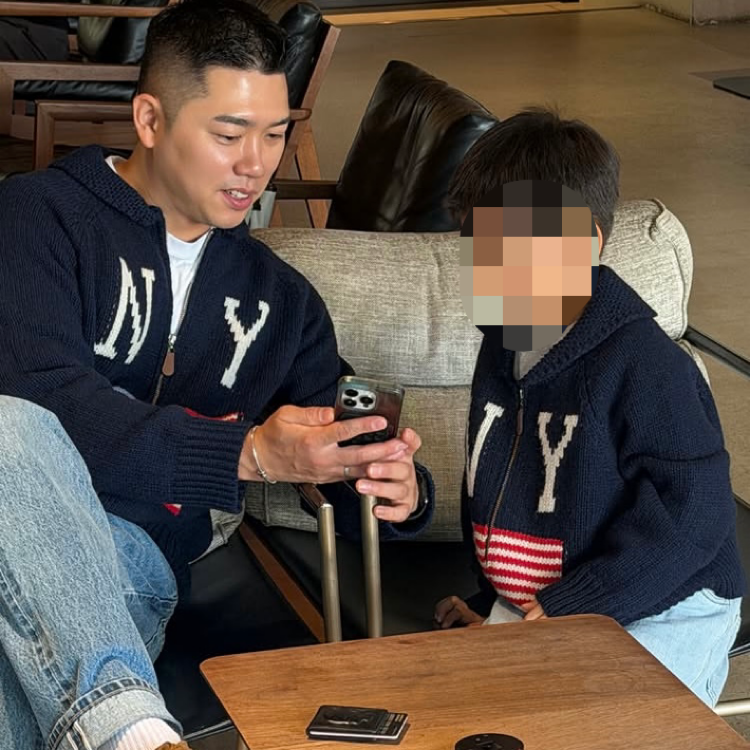 カフェでスマートフォンを見る夫と、顔をぼかした息子。2人は同じ紺色のニットを着ている