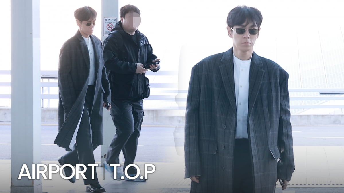 サングラスをかけ、チェック柄のジャケット姿で空港を歩くT.O.P