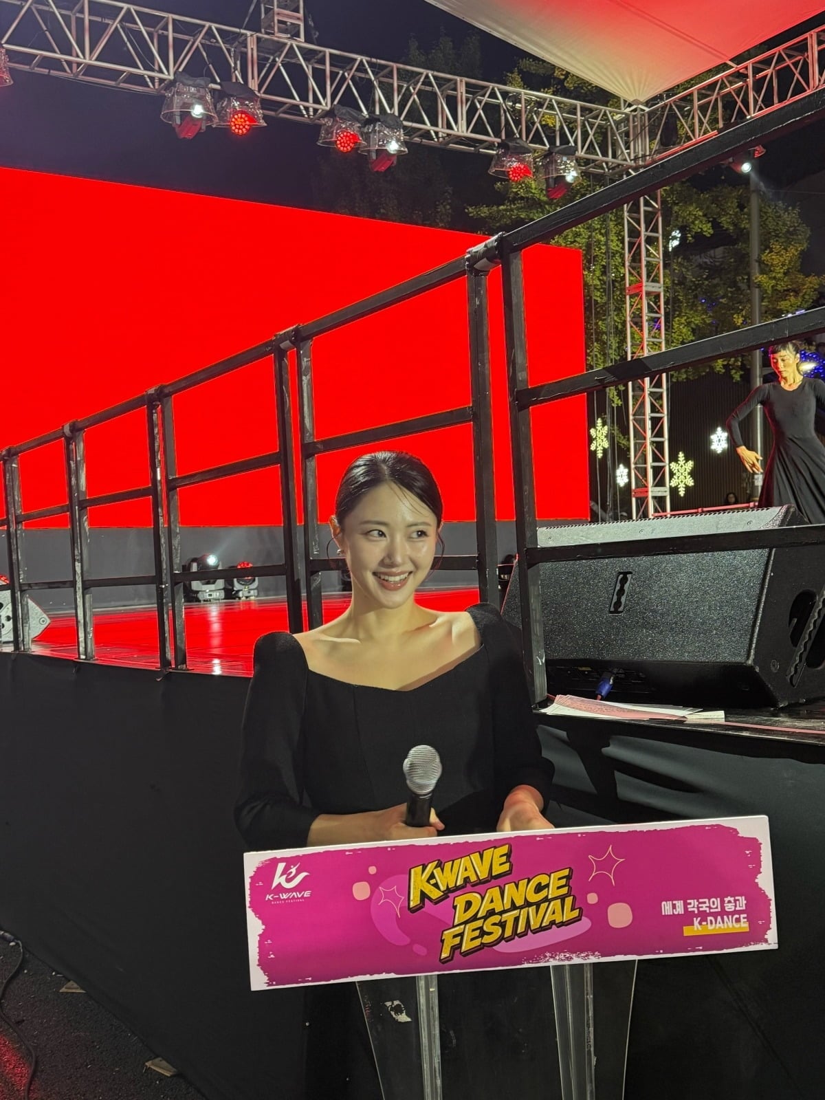 K-WAVE DANCE FESTIVALのステージ脇で、黒いドレス姿でマイクを持つ『私はSOLO』32期ヨンスク