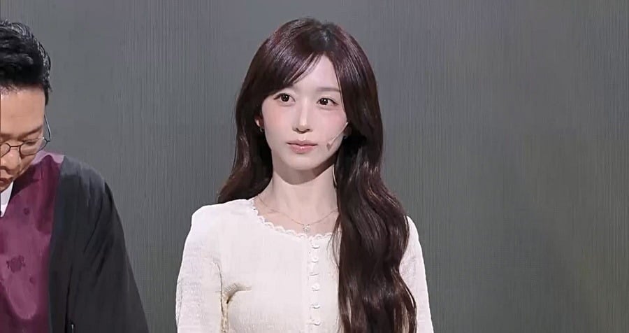 KBS2『ギャグコンサート』の収録で、白いトップス姿で出演者の隣に座るNMIXXのヘウォン