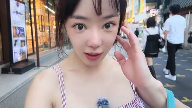 江南の店を訪れ、頬に手を当てながらカメラに笑顔を見せるソウ