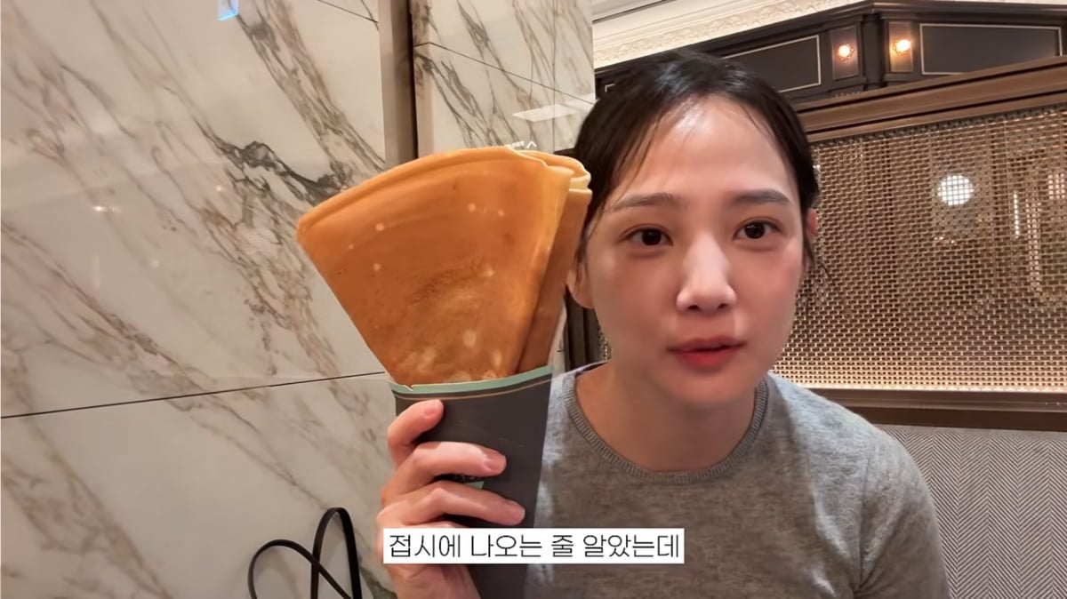 ユン・スンアが韓国のアウトレットで大きな菓子を手に持つ、YouTube動画の一場面