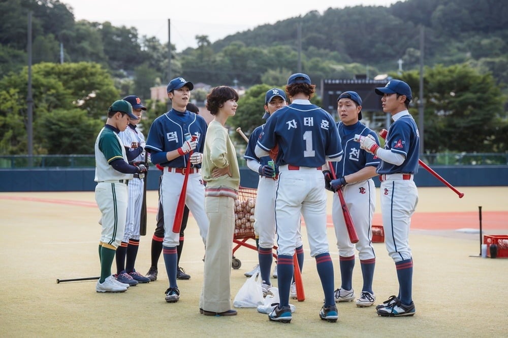 野球場でユニフォーム姿の高校野球部員と教師が集まり、話をするドラマ『ギフト』の場面。