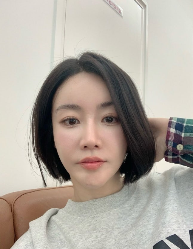 グレーのスウェット姿でカメラを見つめるファン・ウスルヘ。あご下の黒いボブヘアが印象的