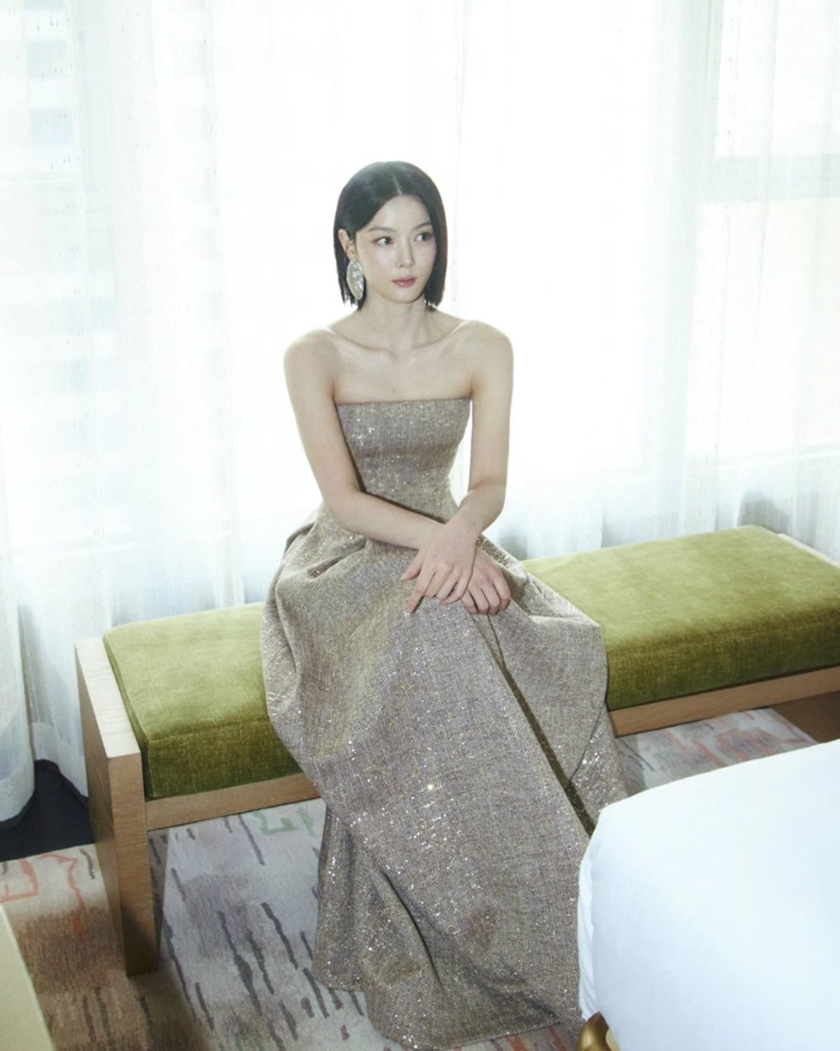 香港でゴールドのチューブトップドレスを着てベンチに座るキム・ユジョン
