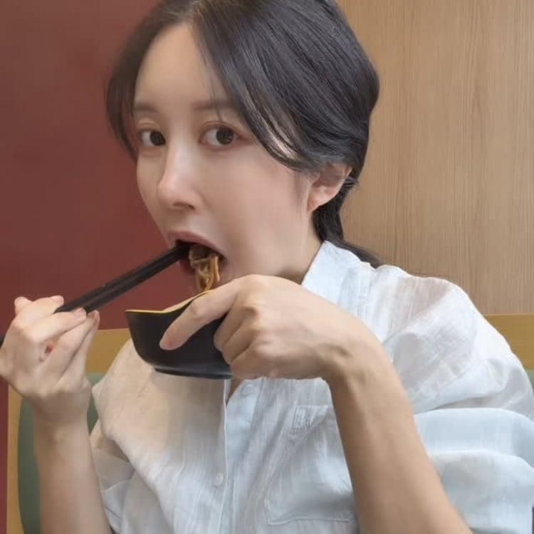 火鍋店で麺を口に運び、食事を楽しむアヤネ