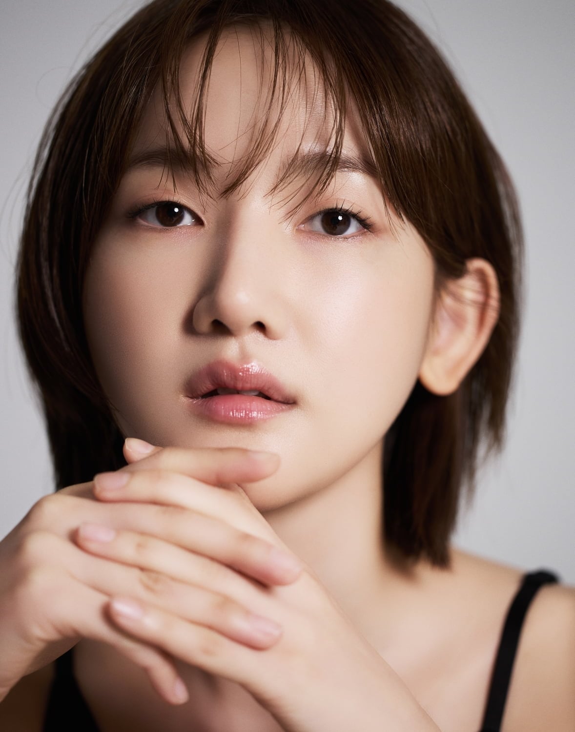 黒いトップス姿で手を重ね、正面を見つめるアン・ソヨのポートレート