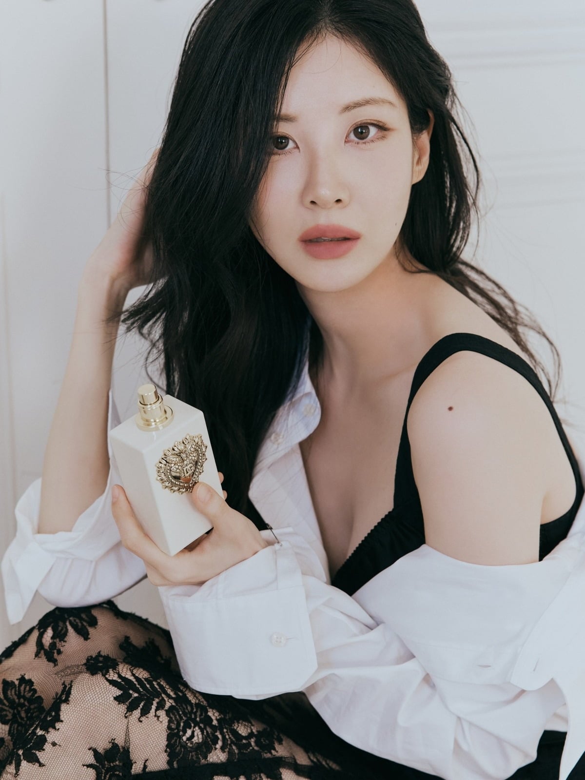 白いシャツと黒いレースの衣装で香水を手にする少女時代のソヒョン