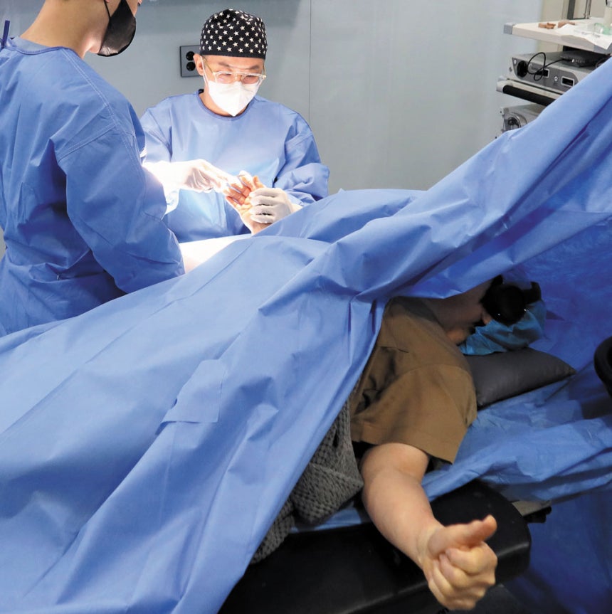 장기준 대표원장이‘수부 각성 수술’을 진행하고 있다.환자는 헤드셋으로 음악을 들으며,사진 기자의 요청에 엄지를 들어보이고 있다./김지아 헬스조선 객원기자