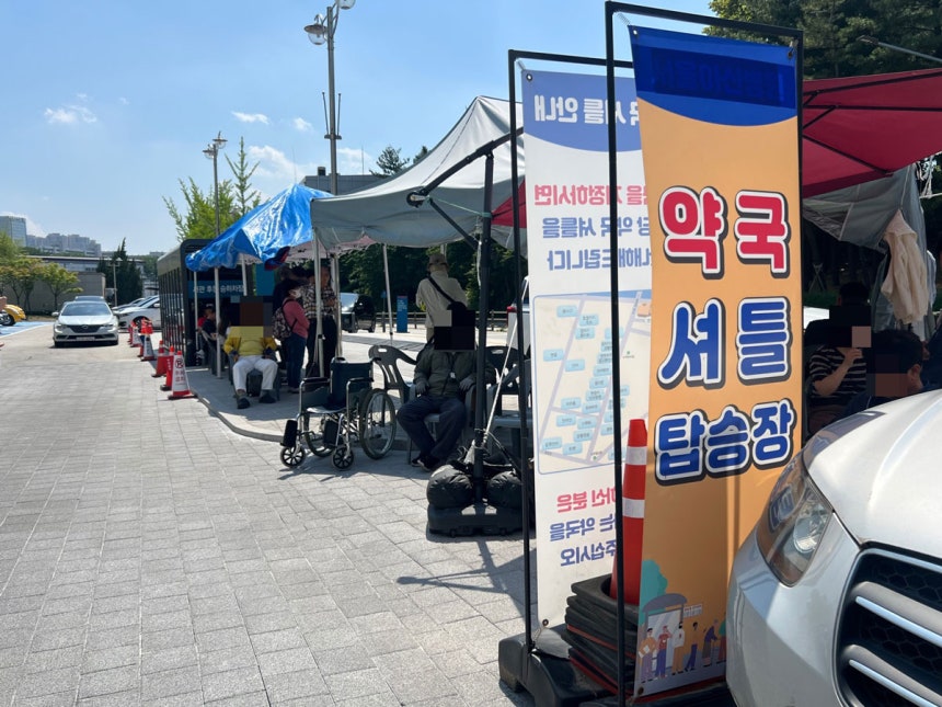 서울아산병원 서관 후문 주차장에 마련된 약국 셔틀 탑승장에서 안내원이 환자들을 향해 목적지 약국을 묻고 있다./사진=구교윤 기자