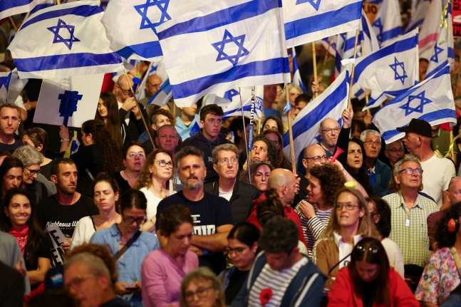 지난 13일(현지 시각) 이스라엘 텔아비브에서 베냐민 네타냐후 총리의 정책에 반대하고, 하마스에 납치된 인질 석방을 요구하는 시위에 참석한 사람들이 이스라엘 국기를 들고 있다. / 로이터