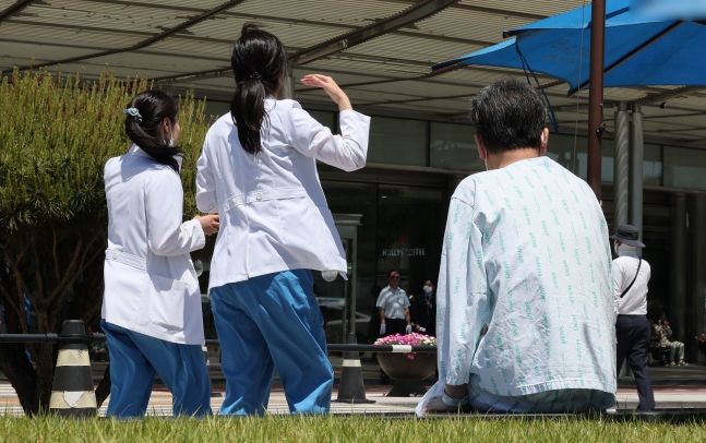 정부의 2025학년도 의대 증원 추진에 대한 법원 판단을 앞두고 있는 가운데 14일 서울 시내의 대형병원에서 한 환자가 휴식을 취하고 있는 가운데, 의료진들이 이동하고 있다. /뉴스1