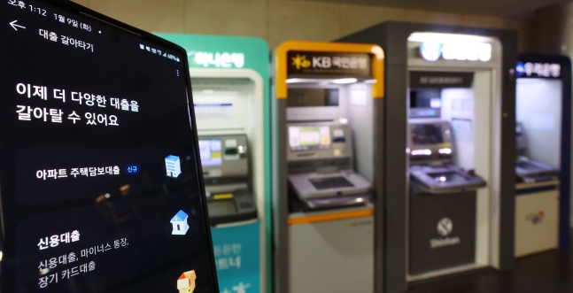 비대면으로 대출을 갈아탈 수 있도록 한 대환대출 비교 플래폼과 서울 시내의 한 건물에 설치된 ATM./연합뉴스