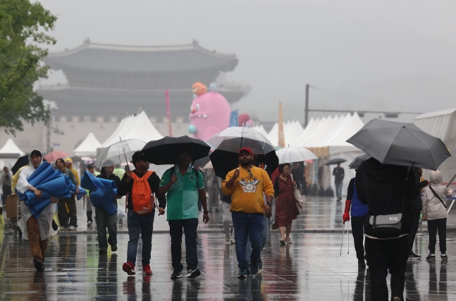 지난 26일 오후 비가 내리는 서울 광화문광장에서 시민들이 우산을 쓴 채 걸어가고 있다. /연합뉴스