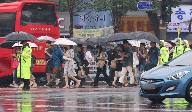 22일 오전 서울 숭례문 인근에서 시민들과 외국인 관광객들, 경찰이 우산을 쓰고 이동하고 있다. /뉴스1
