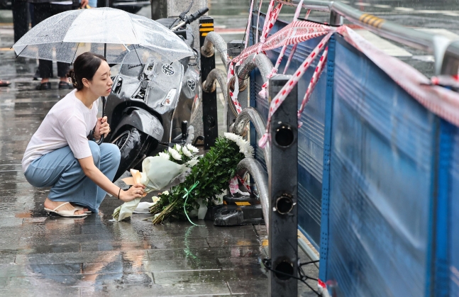 지난밤 승용차가 인도로 돌진해 9명이 사망하는 사고가 발생한 2일 오전 서울 중구 서울시청 인근 교차로 사고현장에서 한 시민이 희생자를 추모하며 헌화를 하고 있다./뉴스1