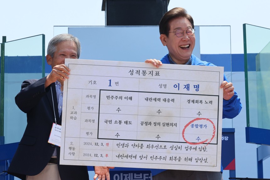 더불어민주당 이재명 대선 후보가 선거를 이틀 앞두고 '험지 공략'에 나선 1일 고향인 경북 안동시의 웅부공원에서 열린 유세에서 이 후보의 초등학교 은사인 박병기 선생님으로부터 대선 후보 모의 성적 통지표를 받고 있다