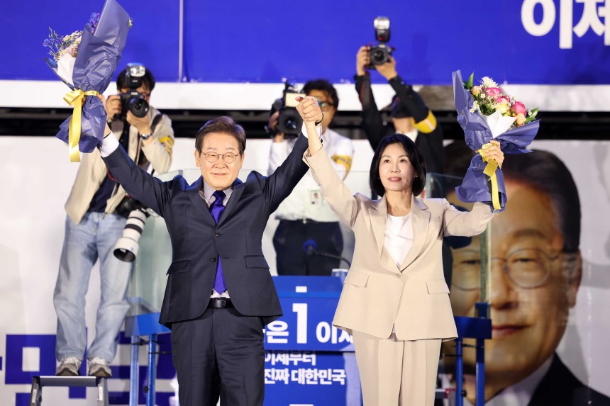 당선이 확실시 되는 이재명 더불어민주당 대선후보와 김혜경 여사가 4일 오전 서울 여의도 국회 앞에서 열린 국민 개표방송 행사에서 꽃다발을 받은 뒤 시민들을 향해 인사하고 있다./뉴스1