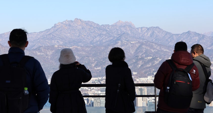 서울 남산을 찾은 외국인 관광객들이 눈이 쌓인 북한산을 바라보고 있다./뉴스1