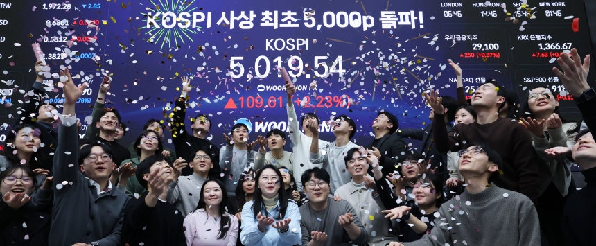 한국 증시가 장중 사상 처음으로 '코스피 5000' 쾌거를 달성한 22일 서울 중구 우리은행 본점 딜링룸에서 직원들이 장중 최고가가 찍힌 전광판을 배경으로 코스피 5000 돌파를 축하하고 있다.이날 코스피는 이재명