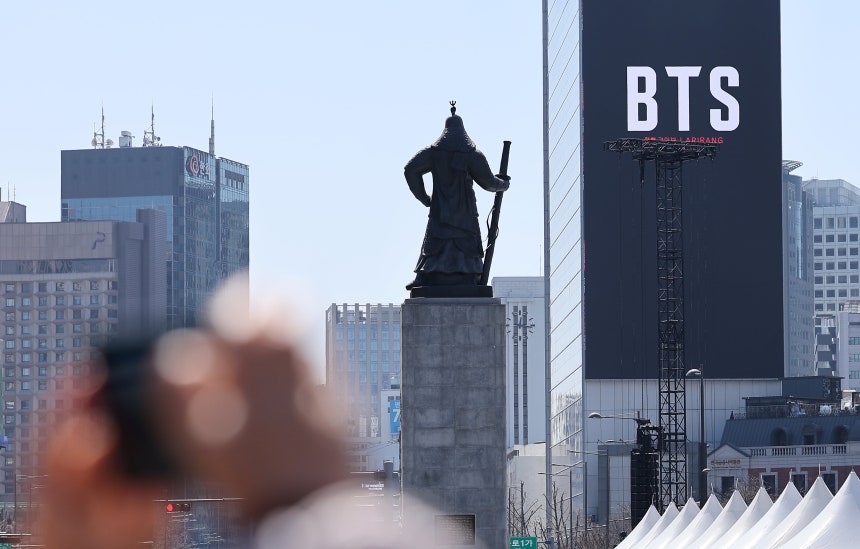 그룹 방탄소년단(BTS)의 서울 광화문광장 컴백 공연이 이틀 앞으로 다가온 19일 서울 종로구 광화문광장에서 시민들이 한 건물 외벽에 부착된 BTS 컴백 공연 광고물을 스마트폰으로 촬영하고 있다./뉴스1