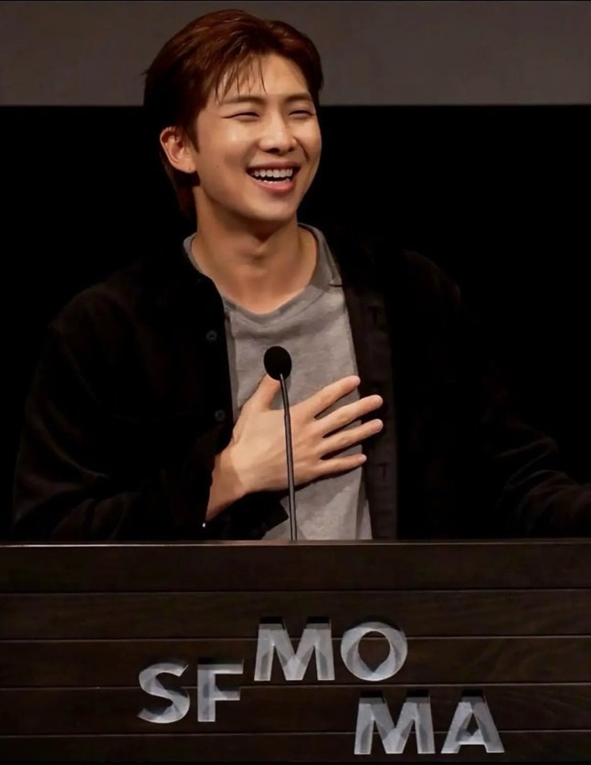 SFMOMAのロゴを背に、笑顔で話すBTSのRM