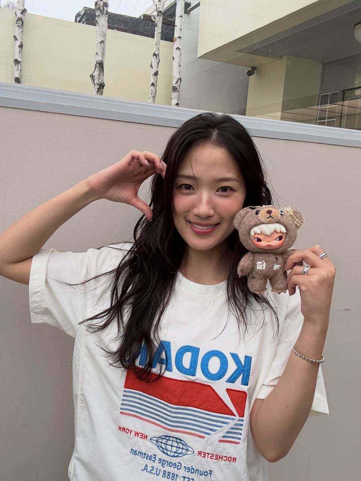 白いTシャツ姿でぬいぐるみを手に持ち、笑顔を見せるキム・ヘユン。