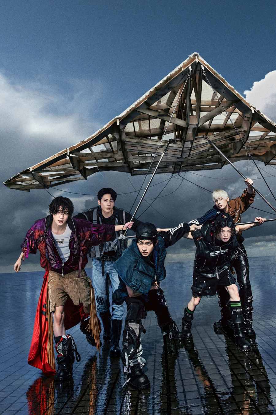 グライダーの下でポーズを取るTOMORROW X TOGETHERの5人