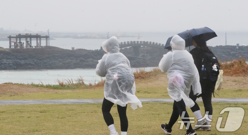 비가 내리는 27일 오후 제주시 조천읍 함덕해수욕장에서 우산을 쓴 관광객들이 이동하고 있다.2025.3.27/뉴스1 ⓒ News1 오현지 기자