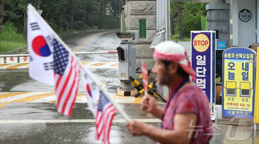 14일 오후 윤석열 전 대통령이 수감된 서울구치소 앞에 한 지지자가 태극기와 성조기를 흔들고 있다. 조은석 내란 특검팀은 이날 윤 전 대통령이 서울구치소 수용실에서 나가기를 거부하는 등 인치 집행에 불응해 15일 오