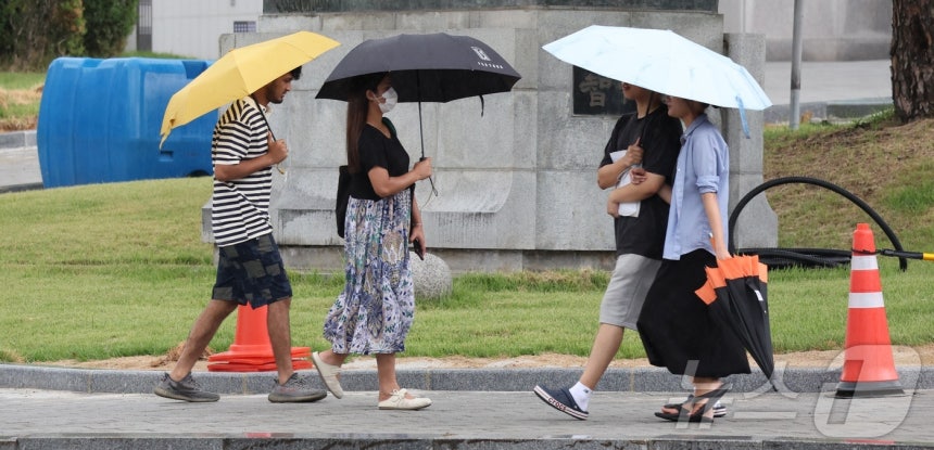 On the 11th, citizens and foreigners with umbrellas are moving along Baekje-daero in Jeonju, Jeollabuk-do, where it is raining.